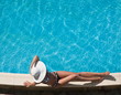 Foto: Young woman sitting on the ledge of the pool. Young woman sitting on the ledge of the pool.