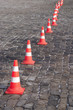 Barrier of red and white cones on the stone pavement