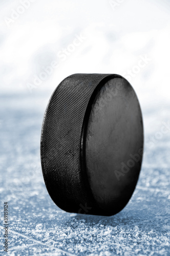 Photo: black hockey puck on ice rink black hockey puck on ice rink