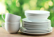 Clean dishes on wooden table on green background Clean dishes on wooden table on green background