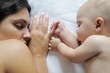 Baby sleeping close to her mother, holding her finger