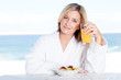 cute young woman drinking orange juice at breakfast table