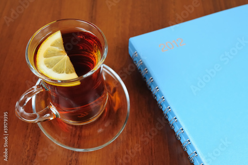 Foto: Cup of tea and notebook on table Cup of tea and notebook on table