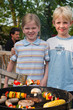 zwei Kinder stehen am Grill
