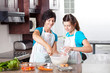 teen daughter helping mother baking in kitchen