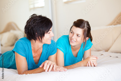 Photo: middle aged mother and teen daughter chatting on bed middle aged mother and teen daughter chatting on bed