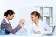 Young women arm wrestling in office