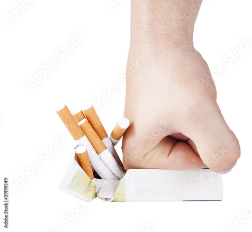 Photo: Man's hand crushing cigarettes on white background Man's hand crushing cigarettes on white background
