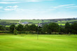 Golf green with a checkered flag, the countryside in background