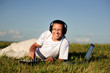 smiling disc jockey lie on green grass and mix music