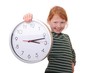 Rothaariges Mädchen zeigt eine große Uhr