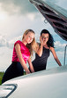 Foto: Two young women with broken car on a road Two young women with broken car on a road