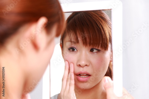 Photo: young woman worries about dry rough skin young woman worries about dry rough skin