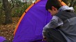 Young man pitching a tent looks at girl