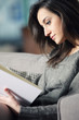 Portrait of a  young woman lying on couch with book