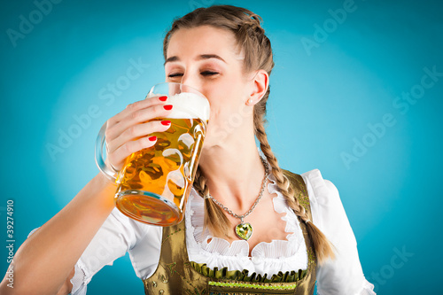 Photo: Junge Frau in Tracht trinkt Bier Junge Frau in Tracht trinkt Bier