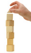 The hand establishes a toy roof on wooden cubes