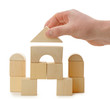 The hand establishes a toy roof on wooden cubes
