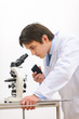 Researcher looking in microscope and making notes