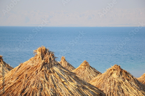 Photo: straw umbrellas on beach against sea straw umbrellas on beach against sea