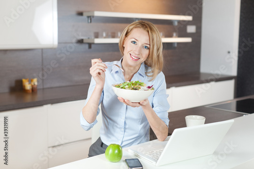 Photo: junge frau isst salat in der küche junge frau isst salat in der küche
