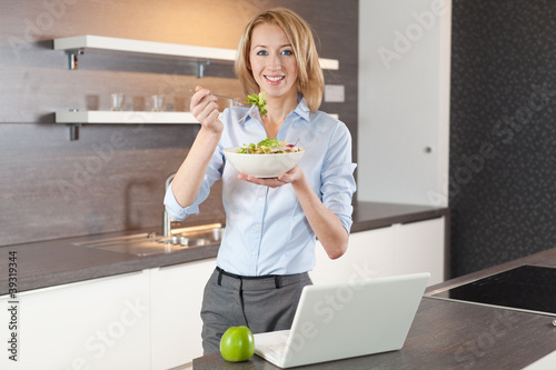 Photo: junge frau isst salat in der küche junge frau isst salat in der küche