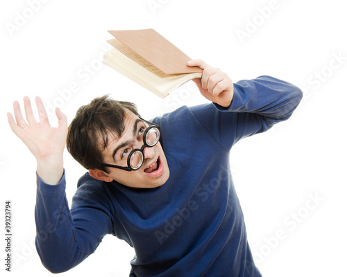 Photo: Student in glasses with a book over his head on white background Student in glasses with a book over his head on white background
