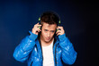 Young man listening music with headphones portrait on blue back