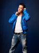 Young man listening music with headphones standing on blue back