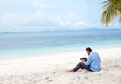 Photo: Business man sitting and working on the beach with Ipad Business man sitting and working on the beach with Ipad