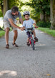 Mid aged man teaching his son to ride a bicycle