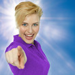 Young woman in front of blue sky points her finger at you