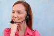Redhead young woman at helpdesk center, smiling