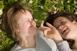 A girl with Down syndrome and her sister laughing in the grass.