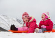 Two laughing kids sledding