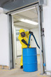 professional in uniform filling large  barrel with chemicals