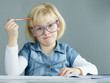 Blonde girl with glasses is concentrated doing her homework