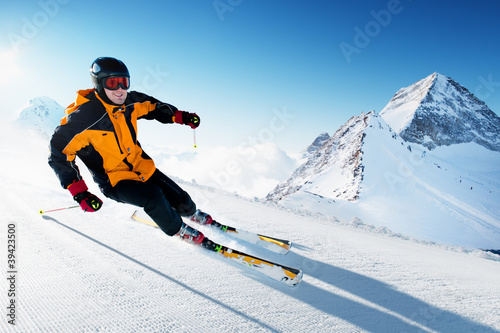Photo: Skier in mountains, prepared piste and sunny day Skier in mountains, prepared piste and sunny day