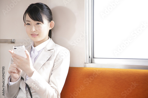 Photo: 電車内でスマートフォンを触るOL 電車内でスマートフォンを触るOL