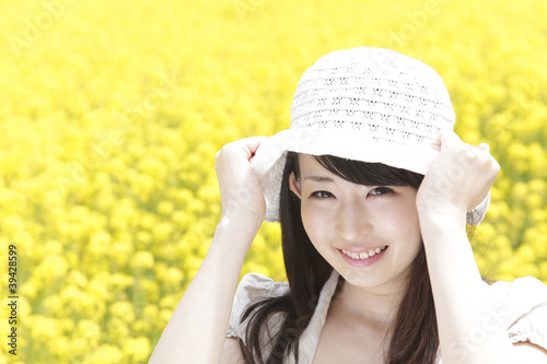 Photo: 菜の花畑で帽子を被り微笑む女性 菜の花畑で帽子を被り微笑む女性