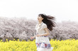 菜の花畑を走る笑顔の女性
