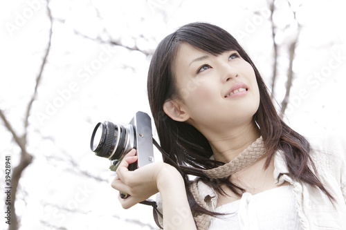 Photo: 桜の下でカメラを持つ笑顔の女性 桜の下でカメラを持つ笑顔の女性