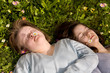 A girl with Down syndrome and her sister resting in the grass.