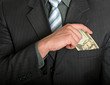 Businessman putting a dollar bill in his pocket
