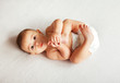Cute baby lying on blanket and holding legs