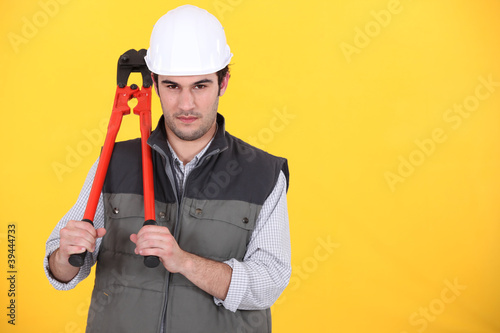 Photo: portrait of craftsman holding spanner against yellow background portrait of craftsman holding spanner against yellow background
