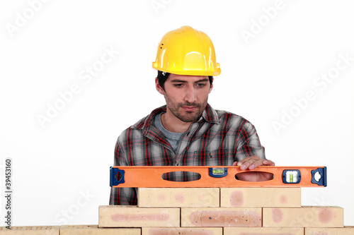 Photo: Mason checking level of a brick wall Mason checking level of a brick wall