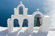 Calm sea, white church arch, cross, bells Island Santorini Greec