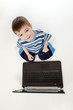 Adorable child playing with laptop. Top view.