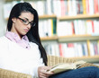 female student reading a book in library